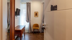Ein Zimmer mit einem Holztisch, einem Stuhl, einem an der Wand befestigten Fernseher und einer Tür mit einem Stadtsticker.