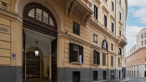Un bâtiment historique doté d’une entrée en arc de cercle, de nombreuses fenêtres et situé sur une rue pavée.