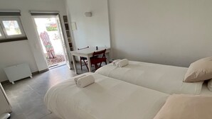 A modern hotel room with two beds, a small desk, and a chair.