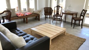 A modern living room with a leather sofa, a wooden coffee table, and several chairs.