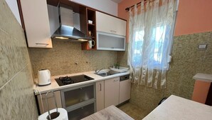 Una cocina compacta con estufa, pileta y una pequeña mesada.