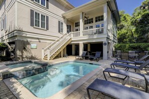 Une maison à deux étages dotée d’une piscine, d’un espace salon extérieur et d’un escalier menant à un balcon.