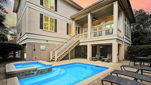 Une maison à deux étages dotée d’une piscine, d’un espace extérieur aménagé et d’un escalier menant à un balcon.