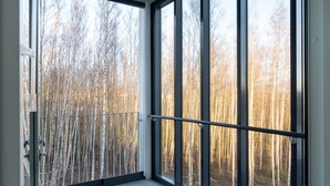 Une pièce dotée de grandes fenêtres donnant sur une forêt.