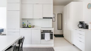 Une cuisine moderne avec des meubles blancs, un four encastré et une machine à café posée sur le plan de travail.