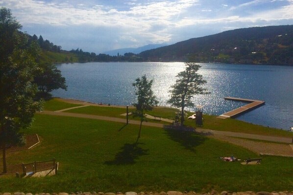 Une vue sur le lac, avec un quai, des pelouses et des arbres.
