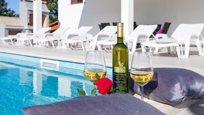 A poolside area with lounge chairs, a bottle of wine, and glasses of wine. - A comfortable home perfect for relaxing in the green heart of Istria (Bokordici)
