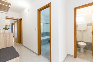 A modern bathroom with a shower, toilet, and a vanity with a plant.