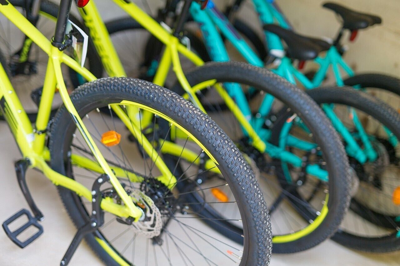 Ein Detailaufnahme eines gelben Fahrrads mit schwarzem Reifen, Teil eines Fahrradständers.