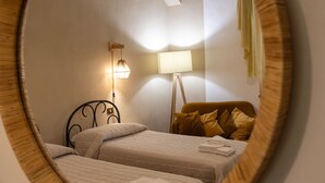 Une chambre avec deux lits, une lampe de chevet et une lampe sur pied.