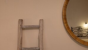 Une échelle en bois appuyée contre un mur, avec un miroir rond et une tête de lit décorative en métal.