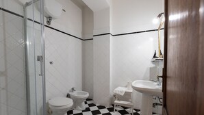 Une salle de bain avec une douche à parois de verre, des toilettes, un bidet et un lavabo sur colonne.