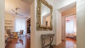 A hallway with a checkered floor, a dining area with a table and chairs, a large ornate mirror, and a ceiling fan. - GuestHost - Testaccio Art & Design Flat BOOK NOW! (Roma)