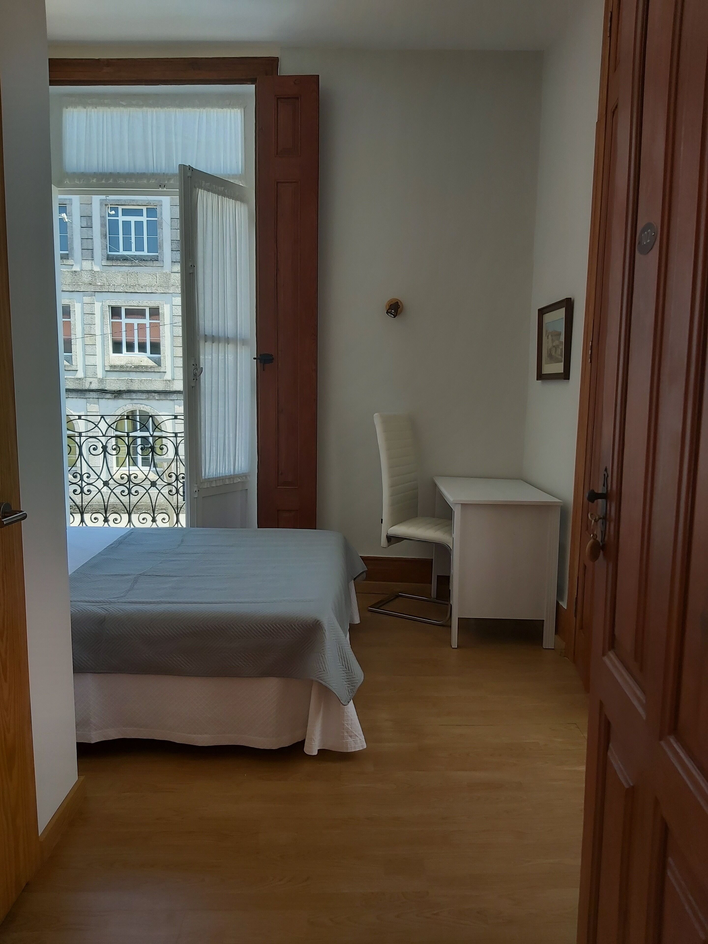A bedroom with a bed, a desk, and a chair.
