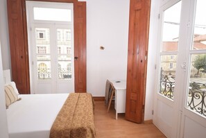 A bedroom with a bed, a desk, and a view through a door.