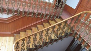 Una escalera de madera con barandillas metálicas ornamentadas y un pasamanos de madera.
