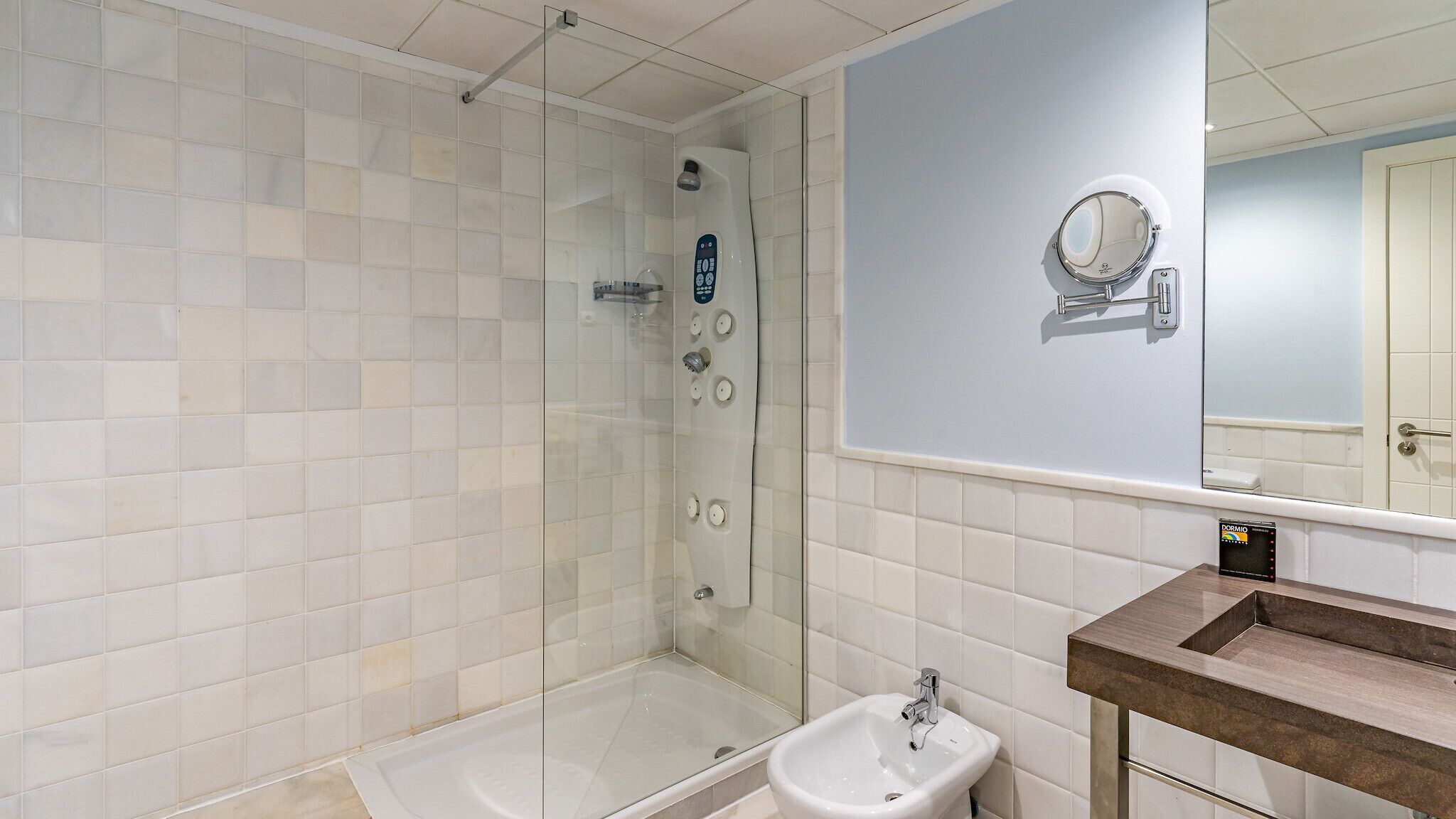 A bathroom with a glass-enclosed shower, a sink, and a mirror.