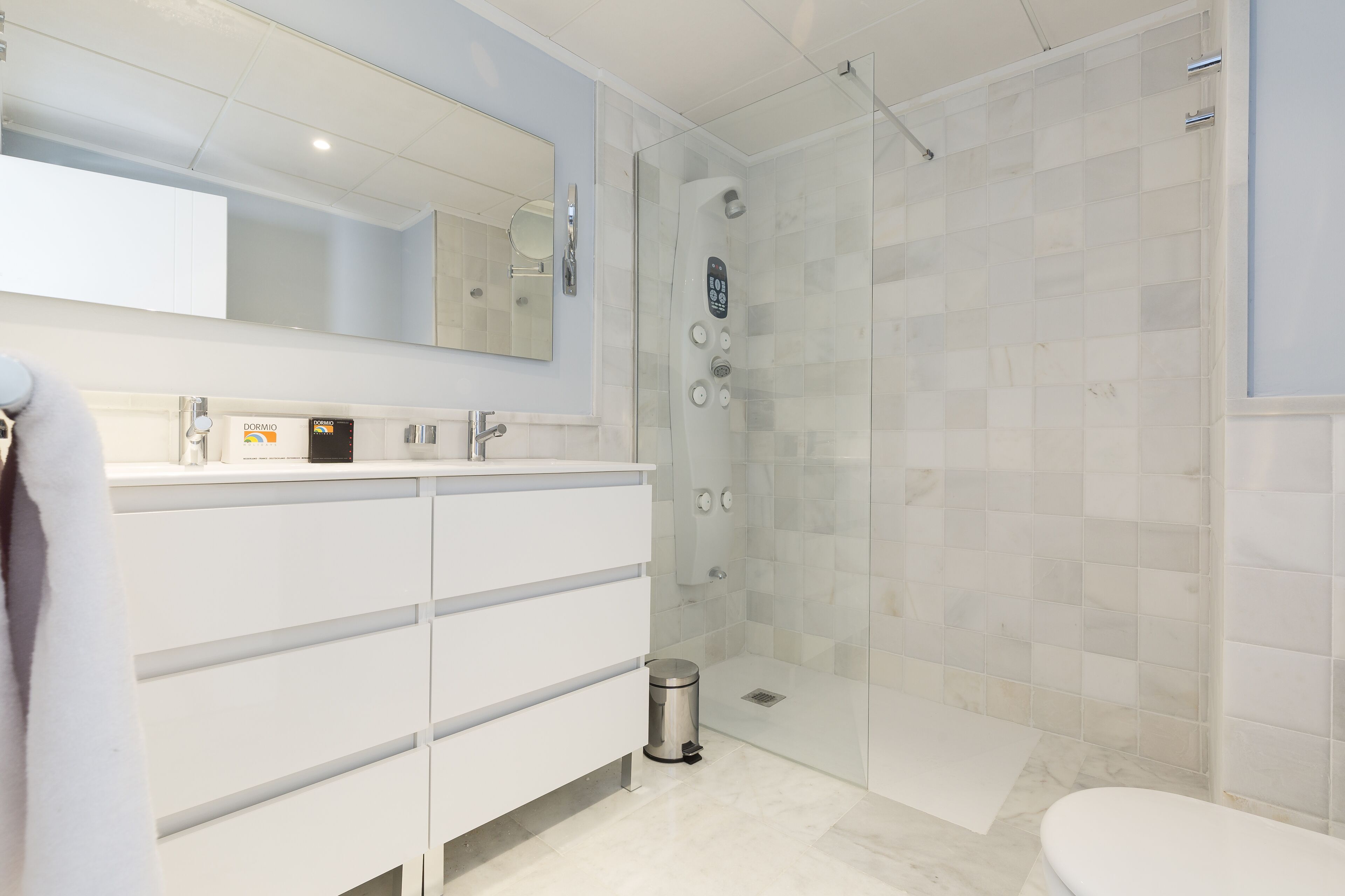 A modern bathroom with a glass-enclosed shower, a white vanity with a mirror, and a toilet.