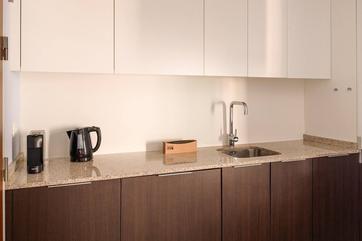 Een keuken met donkerhouten kastjes, een granieten aanrecht, een koffiezetapparaat, een doos en een spoelbak.