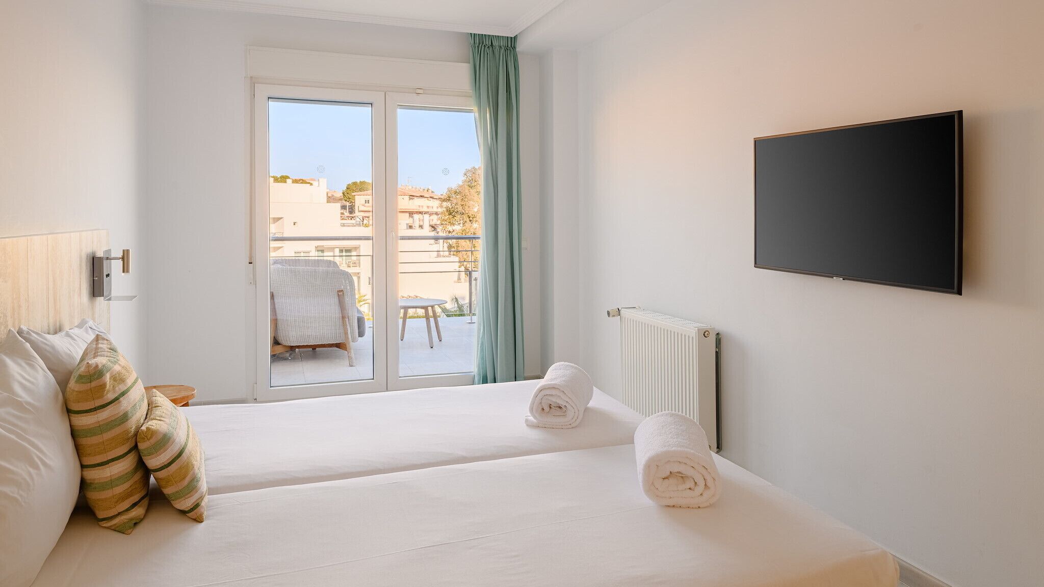 Een hotelkamer met twee bedden, een televisie, een raam met uitzicht en een radiator.