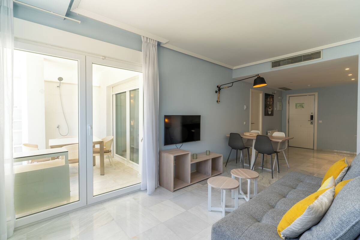 Een moderne woonkamer met een bank, televisie en eethoek.