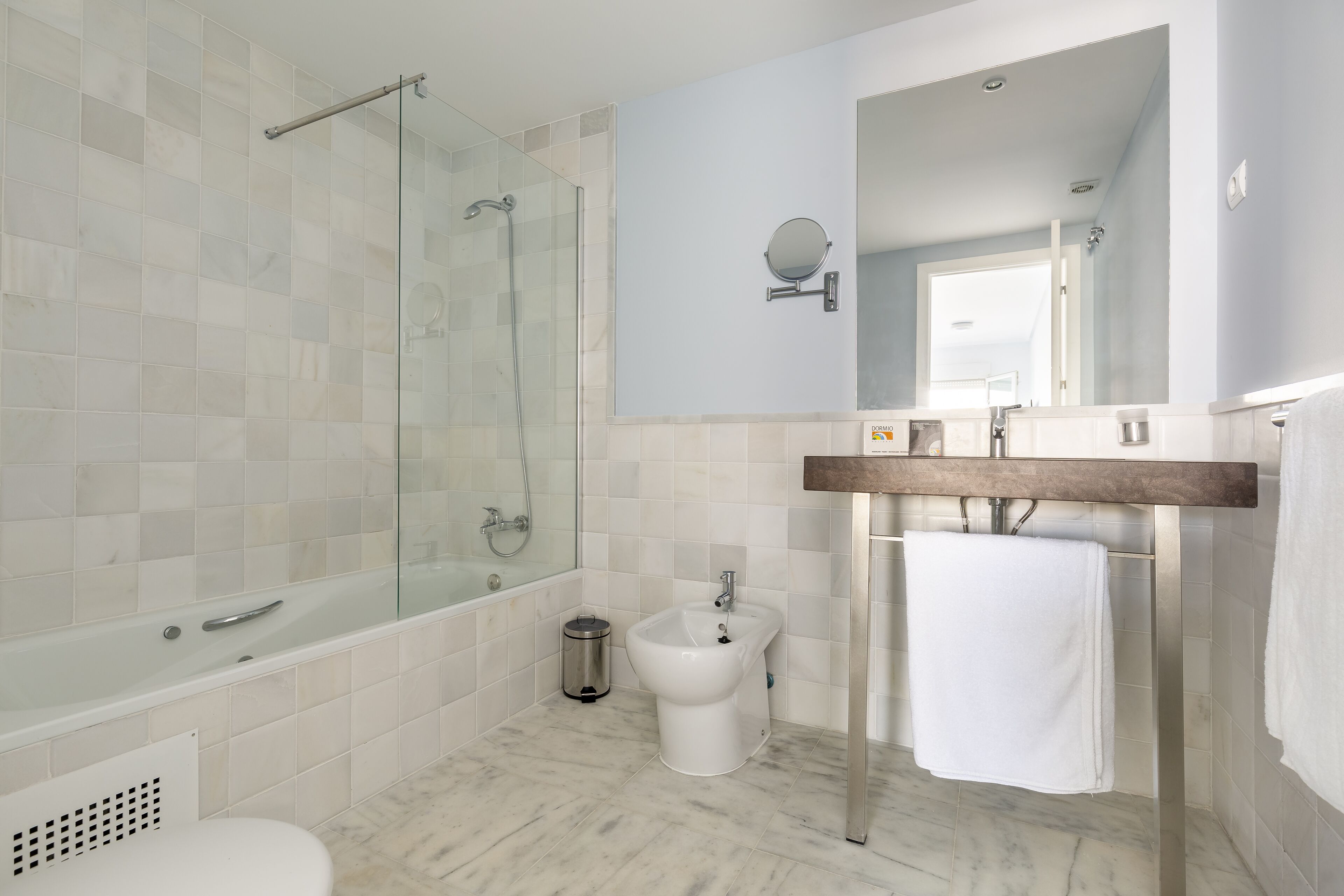 Un baño moderno con ducha de vidrio, un bidé y un tocador de madera con espejo.