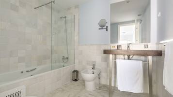 Un baño moderno con ducha de vidrio, un bidé y un tocador de madera con espejo.