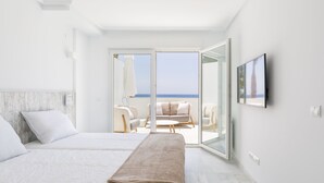 Een moderne hotelkamer met twee bedden, een balkon met uitzicht op zee en een flatscreen televisie aan de wand.