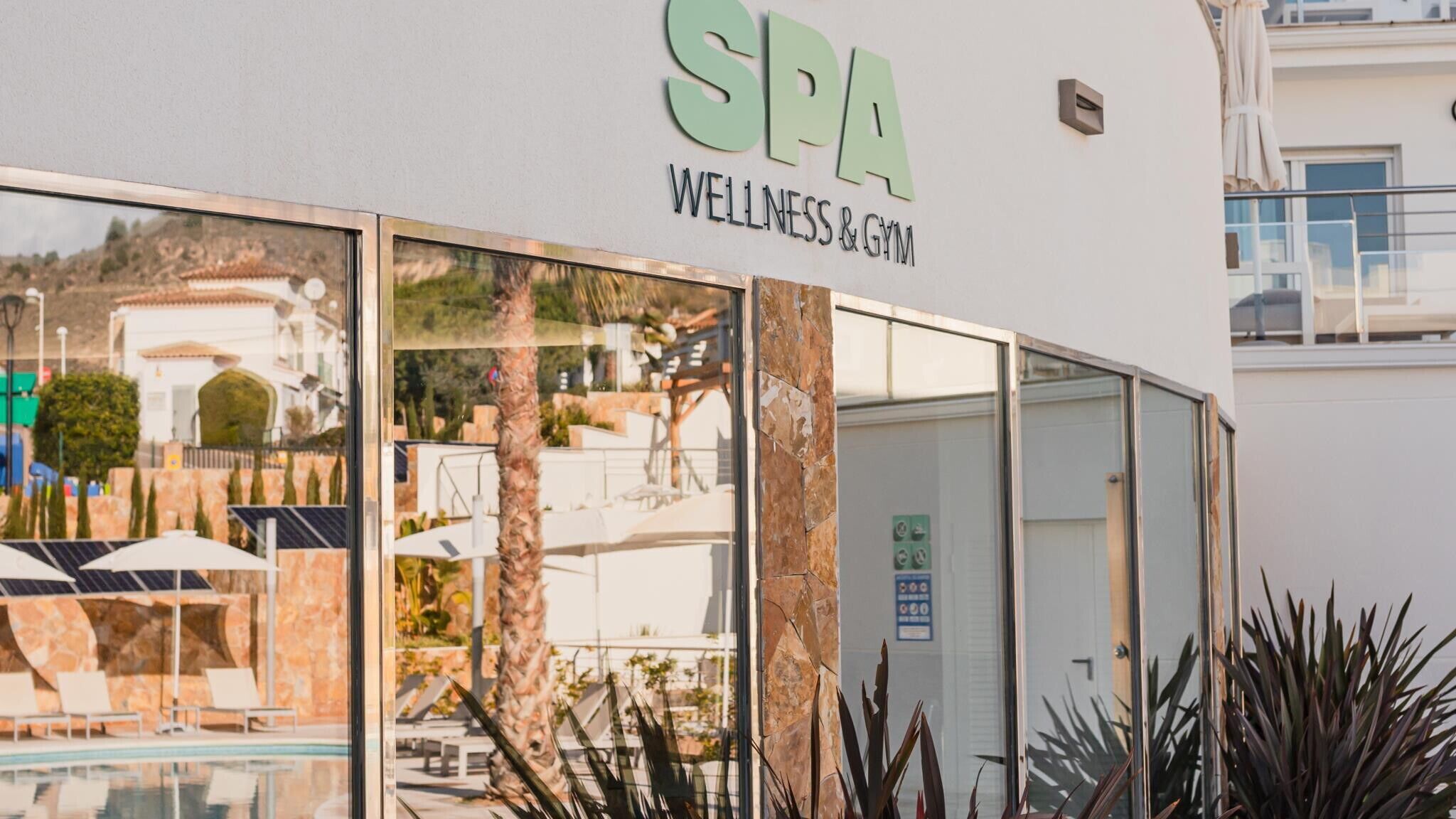 A spa wellness and gym with a glass facade, outdoor seating, and a pool area.