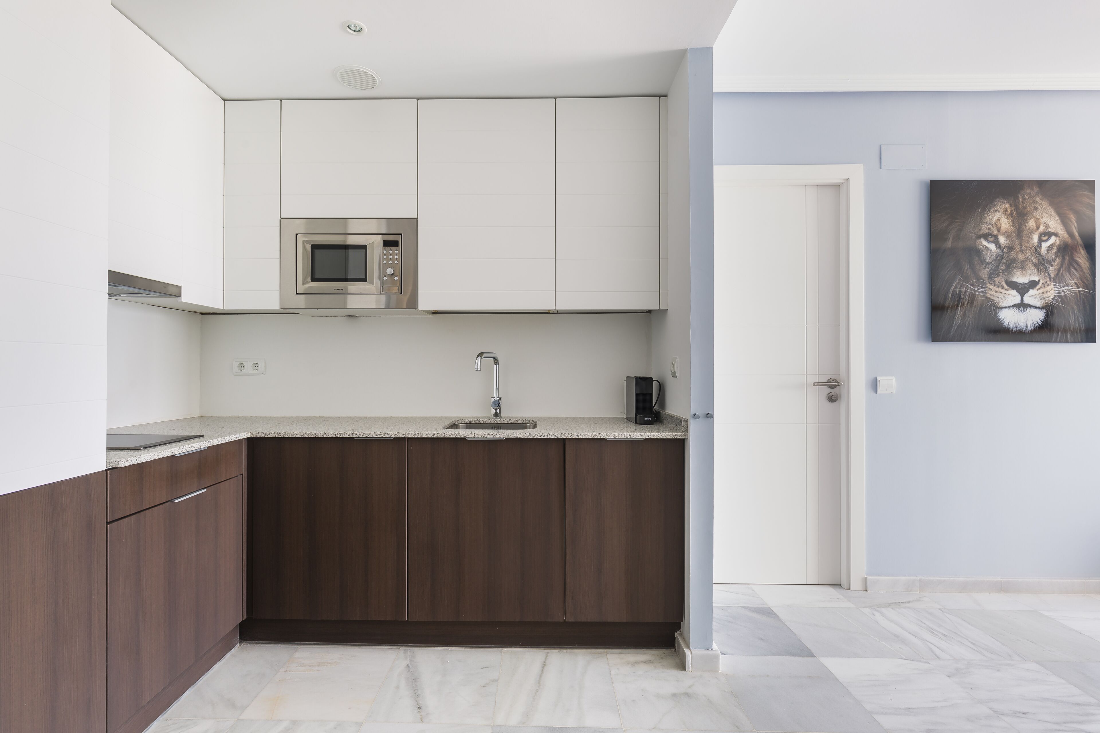 A modern kitchen with dark wooden cabinets, a stainless steel microwave, and a coffee maker.
