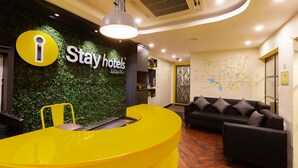 A reception area with a bright yellow desk, a black sofa, and a green wall with a map. - IStayHotels  Jubilee Hills  Hyderabad (Hyderabad)