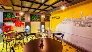 A dining area with tables and chairs, a mural of a mosque, and a sign reading "Stayhotel." - IStayHotels  Jubilee Hills  Hyderabad (Hyderabad)