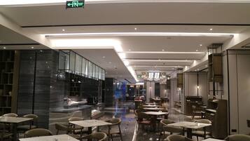 A modern restaurant with a clean, minimalist design, featuring a long counter and multiple dining tables.