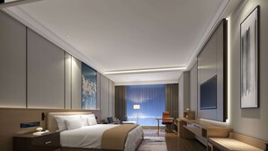 Una habitación de hotel moderna con una cama grande, mesita de noche, escritorio y silla.