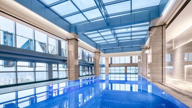 Una amplia piscina cubierta con techo de cristal y vistas a la ciudad.