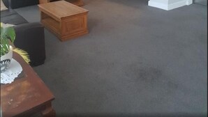 A living room with a sofa, coffee table, and a dining table with a plant. There is a kitchen area with wooden cabinets and a chandelier. - OYO Gran Canaria Hotel (Folkestone)