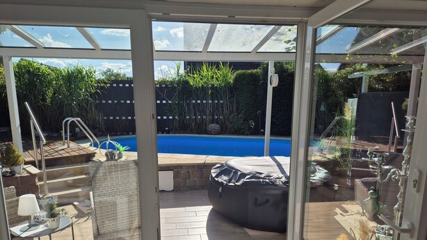 A sunlit patio with a pool, outdoor seating, and a covered grill area. - Luxurious apartment in the beautiful Elbmarschland (Tespe)