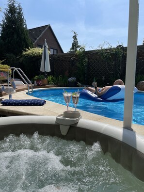 A hot tub with bubbles, a pool, and a person lounging on an inflatable float.
