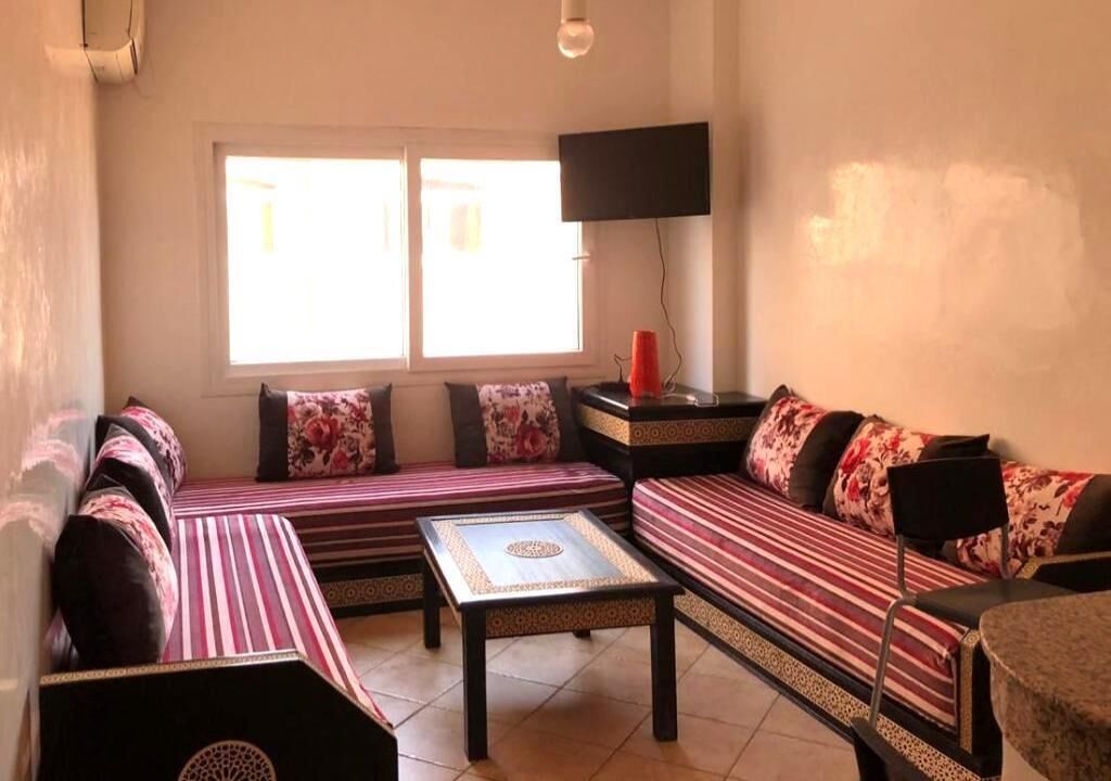 A living room with a sofa set, a coffee table, and a TV mounted on the wall.