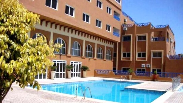 Ein Hotel mit Schwimmbad, mehreren Balkonen und einer gefliesten Liegefläche.