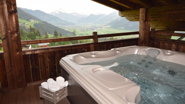 A hot tub with a wooden deck and a view of mountains.