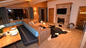 A cozy living room with a fireplace, a sofa, a dining table with plates, and a cowhide rug.