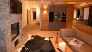 A cozy living room with a stone fireplace, a wooden ceiling, a sofa, and a table with candles and a remote control.