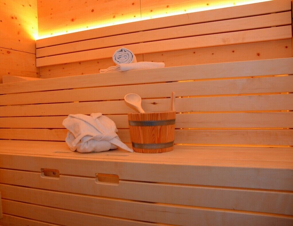 A wooden bench with a towel and a wooden bucket with a spoon.