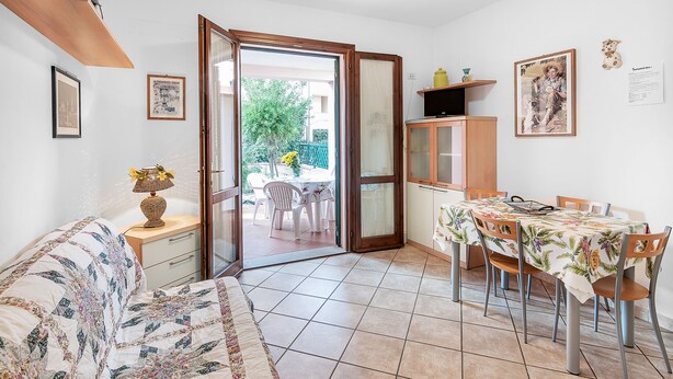 Une pièce comprenant un lit, une table à manger avec des chaises, un petit meuble et une porte donnant sur un espace extérieur.