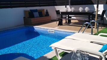 Una piscina al aire libre, tumbonas