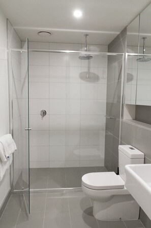 A modern bathroom with a glass-enclosed shower, a white toilet, and a white sink.
