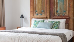 A neatly made bed with a patterned bedspread and pillows, a bedside lamp, and a wooden headboard with decorative elements. - Cosy 3 Bedroom Villa in Freeman's Bay (Auckland)