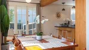 A dining area with a wooden table, chairs, and a potted plant. - Cosy 3 Bedroom Villa in Freeman's Bay (Auckland)