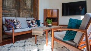 A living room with a sofa, armchair, coffee table, and a television on the wall. - Cosy 3 Bedroom Villa in Freeman's Bay (Auckland)
